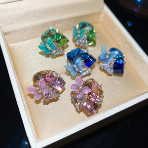 Close-up of crystal flower cluster earrings with butterfly accents and pearls in a box