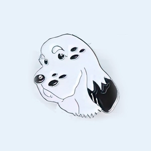 Detailed close-up of a surrealist enamel puppy dog brooch with multiple black eyes