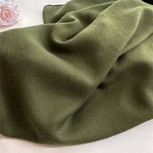 Close-up of green cotton linen fabric texture with soft drape and vintage floral detail