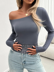 Detail of grey off-shoulder long sleeve top featuring grey lace patchwork hemline