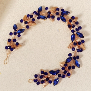 Detailed shot of golden metal wire hair vine with blue crystal beads and leaves