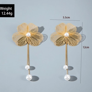 Vue détaillée de boucles d'oreilles fleurs dorées avec pétales tissés et perles