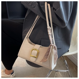 Detail of cream white faux crocodile baguette bag with gold buckle and silk scarf accents