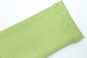 Macro shot of double-needle stitching on light green elastic knit fabric of sports jacket