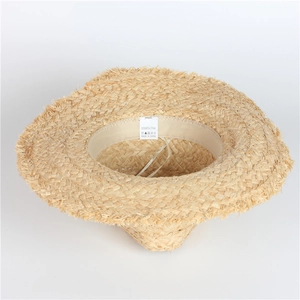 Détail macro du chapeau en raphia naturel avec étiquette de lavage et bords effilochés