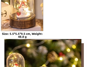 Close-up of a Christmas snowman glass dome ornament with warm LED lights and wooden base
