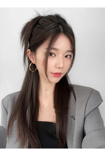 Golden twisted geometric hoop earrings worn by a model in a sophisticated setting