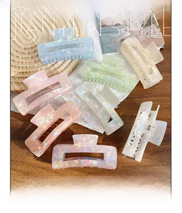 Detail of pearlescent marble texture large hair claw clips on a wooden tabletop