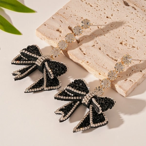 Elegant dark bow earrings featuring sparkling crystals and drop zircons on a white stone