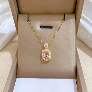 Macro view of a gold-plated necklace with a pink oval gemstone in a luxury gift box