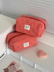 Vista detallada de las bolsas de maquillaje acolchadas con cuadros rojos y blancos