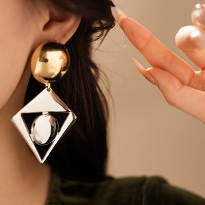 Detail of model wearing large gold circle and silver geometric diamond drop earrings