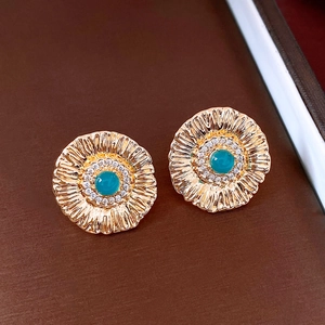 Macro view of flower-shaped stud earrings with cyan gemstone and gold plating