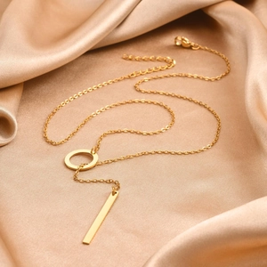Close-up of golden stainless steel Y-pendant necklace on elegant champagne silk fabric