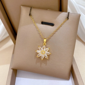 Detail of flower pendant necklace with diamonds on a soft beige jewelry display