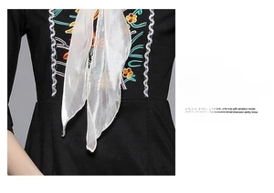 Detailed close-up of intricate floral embroidery and silk bow on a vintage black dress