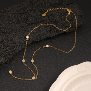 Detailed view of a gold chain necklace with round zircon crystals and lobster clasp closure