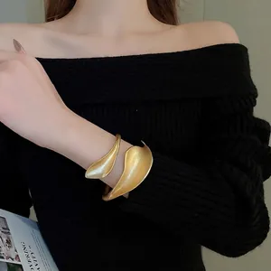 Matte gold irregular organic cuff bracelet with a flowing liquid metal design on wrist