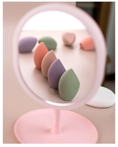 Macro shot of assorted colorful soft makeup sponges framed through a creative pink circle