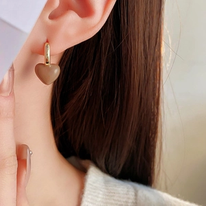 Close-up of a gold-plated heart pendant earring worn by a model in a minimalist style