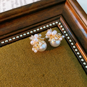 Nahaufnahme von Perlenohrringen mit Zirkonia und Goldmetall auf braunem Vintage-Stoff