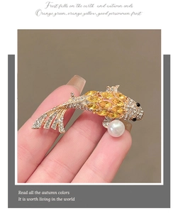 Macro shot of koi fish brooch with yellow gemstones, rhinestones and a white pearl