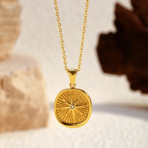Macro view of 18K gold-plated starburst medallion pendant with a sparkling zircon inlay