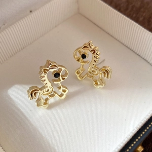 Detail view of 18K gold plated horse stud earrings with black stone eyes in a jewelry box