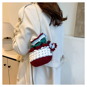 Detailed knit bucket bag with cherry charms and pearl strap on trench coat