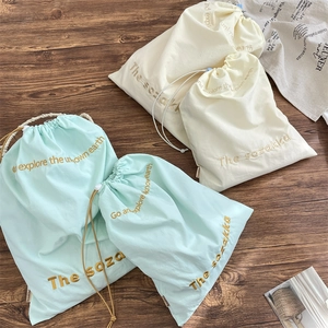 Drawstring fabric storage bags in mint green and cream with letter embroidery