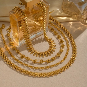 Exaggerated chunky gold geometric chain necklaces layered on silk and perfume props