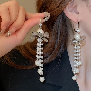 Close-up of elegant long pearl tassel earrings with silver leaf design on a model