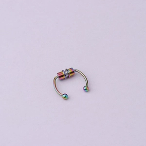 Close-up of a rainbow-colored magnetic septum nose ring over a purple background