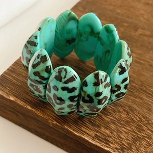 Close-up of turquoise resin cuff bracelet with leopard print pattern and wood grain texture