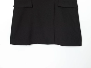 Dettaglio del tessuto twill nero con tasca elegante su un abito corto sartoriale