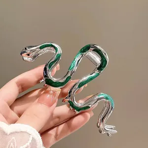 Detail of silver snake hair claw with green enamel finish held in hand for hair styling
