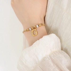Franse stijl gouden armband met strass letter G hanger gedragen op een elegante pols