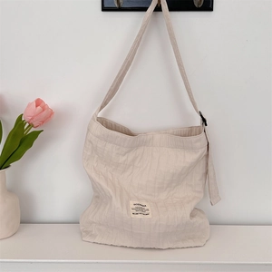 Detailed close-up of cream canvas tote bag showing striped texture and brand patch