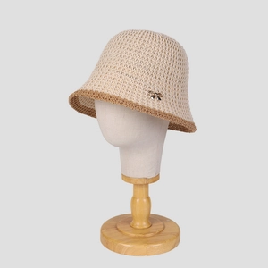 Beige breathable knit bucket hat with brown trim and small metal bow accessory