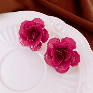 Boucles d'oreilles élégantes rose 3D pêche sur une assiette en céramique blanche