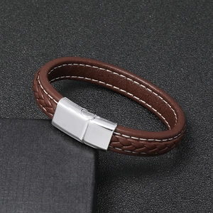 Detail of brown braided leather bracelet with white stitching and silver magnetic clasp