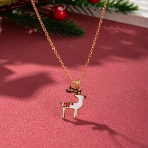 Detailed view of a gold Christmas reindeer necklace with white enamel on a festive red background
