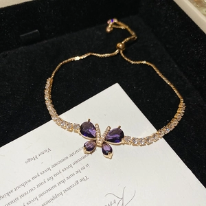 Gros plan du bracelet doré à chaîne ajustable avec pendentif papillon en zircon violet