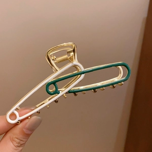 Detail of a minimalist metal hair claw clip with white and dark green enamel finish