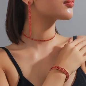 Detailed set of gold choker necklace, bracelet and tassel earrings with red rhinestones