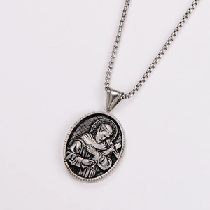 Macro view of silver oval religious pendant with embossed figure holding a cross