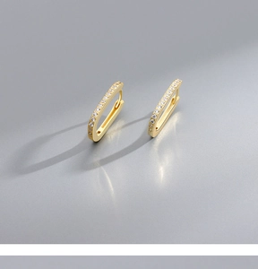 Detail of golden U-shaped earrings with micro-set white cubic zirconia stones