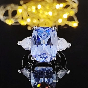 Macro shot of silver ring with pale blue cushion cut center stone and side pear diamonds