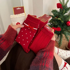 Three-pair Christmas crew socks set with red bows and knit patterns in festive gift packaging