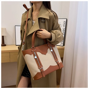 Detail of color-block tote bag with metal zippers and leather buckle on trench coat
